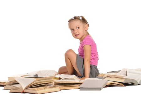 nice little barefooted girl sitting on the pile of open of books and smiling isolated on white backgroundの写真素材