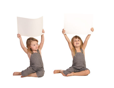 two pretty barefooted twins sisters in rompers holding blank paper sheets above their heads isolated...
