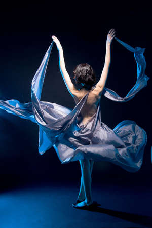girl in a gray dress flying on a black background with blue backlight
の写真素材