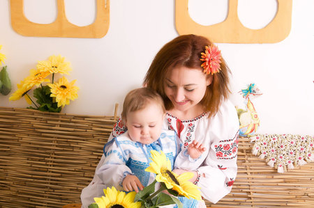 Mother playing with her little daughter. In the Ukrainian national costumes