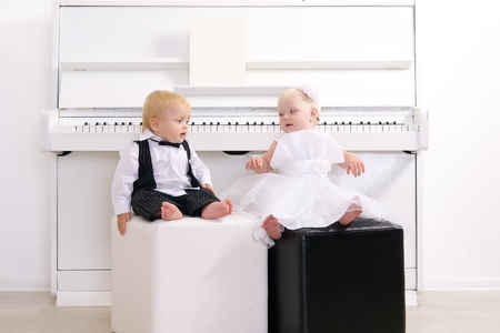 boy and girl in a suit sitting in a concert interior reins white pianoの写真素材