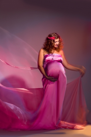 beautiful pregnant woman in a pink fabric flying, shooting mixed lightの写真素材