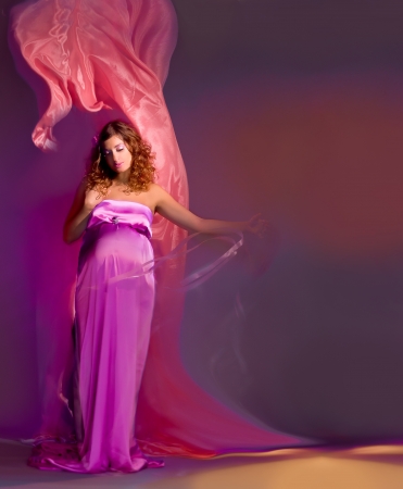 beautiful pregnant woman in a pink fabric flying, shooting mixed lightの写真素材