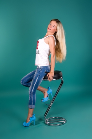 sexy blonde sitting on a bar stool, on a green backgroundの写真素材