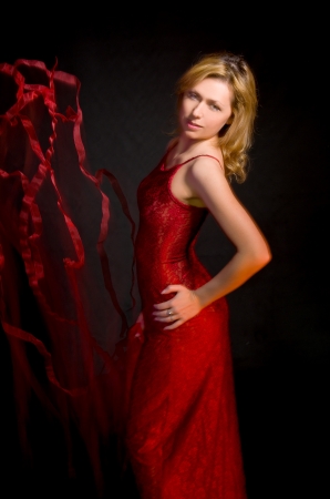 beautiful girl in red dress and ribbon on  black backgroundの写真素材