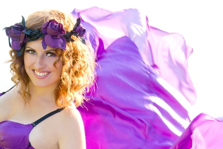 portrait of a beautiful girl with curly hair flying in the purple dress on the background of the riverの写真素材