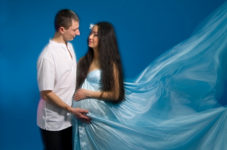 Asian pregnant woman in a silk dress on a blue background. Shooting with a mixed lightの写真素材