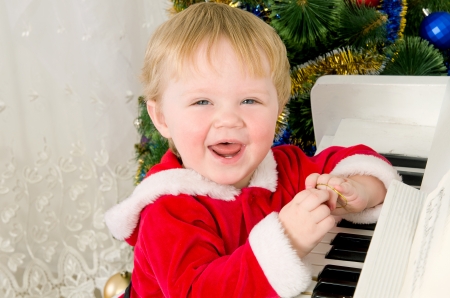 Boy dressed as Santa Claus near the white pianoの写真素材