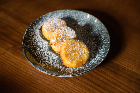 dish of sweet cheese pancakes on brown wooden background