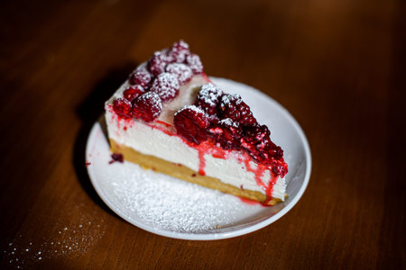 juicy slice of raspberry cheesecake on brown wooden table background
