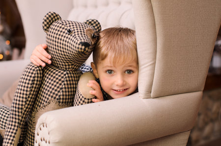 happy little blond boy hugging his mom lying on the floor, near gift boxes, against the backdrop of a christmas treeの写真素材