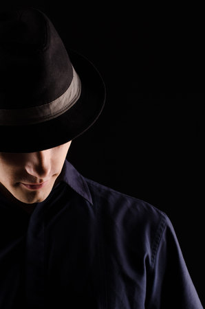 Portrait of a young man in a hood, close-up, against a black background, studio light