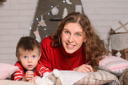 portrait of mother and son hugging and kissing, sitting on the floor in the room, casual clothing...