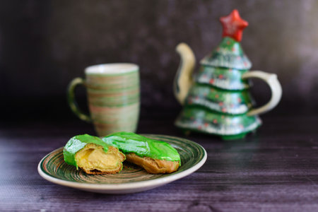 green eclairs with a cut and cream, on a ceramic plate on a dark backgroundの写真素材