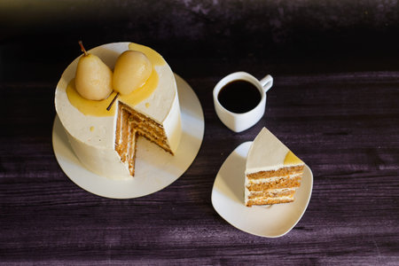 carrot cake, decorated with pears, with a piece cut off next to it, on a saucer