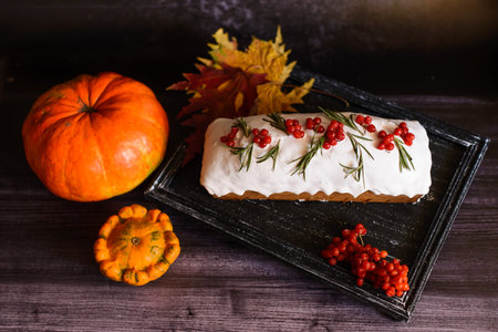 festive cupcake, decorated with viburnum, on a dark tray, next to pumpkinsの写真素材