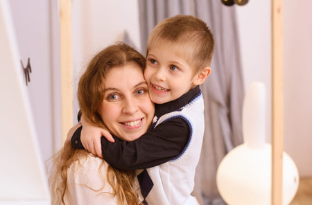 portrait of a happy boy who hugs a smiling mom, in the interior of the roomの写真素材