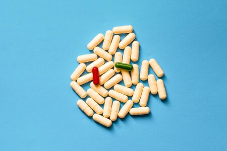 White, green and red pills on a blue background.の写真素材