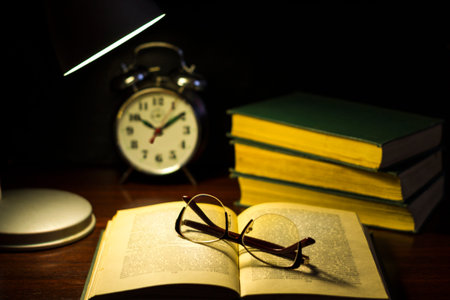 Book and glasses on table.Evening readings under the lamp.
