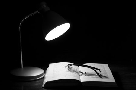 Book and glasses on table.Evening readings under the lamp.
