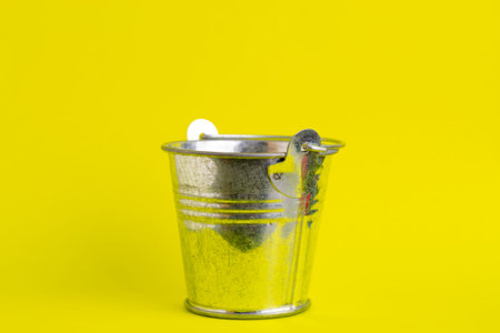 Empty metal bucket on a yellow background close-up.