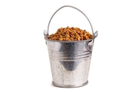 Buckwheat in a metal bucket on a white isolated background.