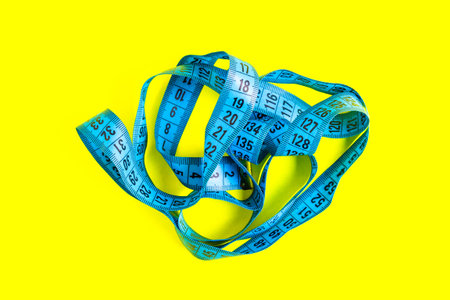 Blue measuring tape on a yellow background. Diet concept