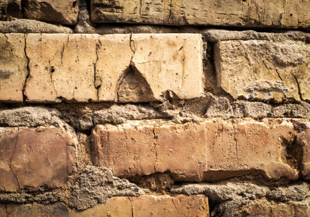 Fragment of old brickwork. Old cracked bricks with cement. Stone wall of an ancient building.の写真素材