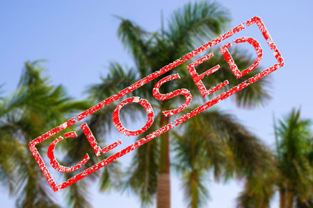 Blurred background of palm trees with closed stamp sign. A ruined vacation. Unlucky holiday season...