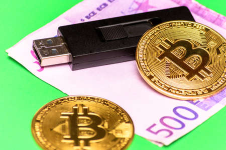 Bitcoin, euro banknote and usb flash drive on a green table.の写真素材