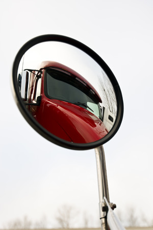 Red truck is reflected in a round mirror on a light backgroundの写真素材