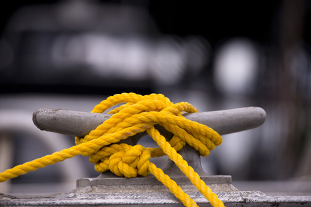 Yellow mooring rope node on the grey metall hook and blurred black and white の写真素材