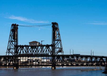 Classic old metal bridge truss lift with the lifting mechanism on the two towers over the River Willamette, Portland, Oregon on a background of blue sky with cloudsのeditorial素材