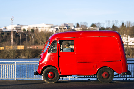 Red retro car with a fisherman waiting fish standing on the river pier on the city and the skyの写真素材