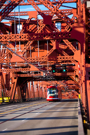 City tram on a red car and a pedestrian drawbridge metal made of riveted structures constituting the mass of triangles for strength.のeditorial素材