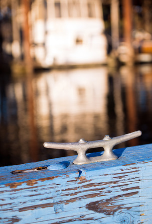 Mooring metal bracket on wood painted in blue berth for boats, yachts or marine on the background blurred parking yachts and boats for mooring and floating mounting means.の写真素材