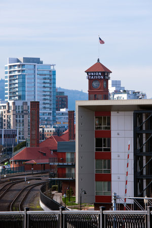 Landscape of a modern city with high multi-storey buildings modern architecture look of concrete and glass with aluminum and rails, red roofs and tower of train station with clock, sign and flag in Down Town Portland.のeditorial素材