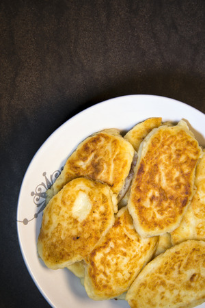 Nutrient ruddy fried potato pancakes in the form of pastries laid out on a plate and ready to eat at the family dinner table. It refers to a handmade food and contains a lot of mineral and nutrients compounds for healthy organism. The dish is part of a poの写真素材