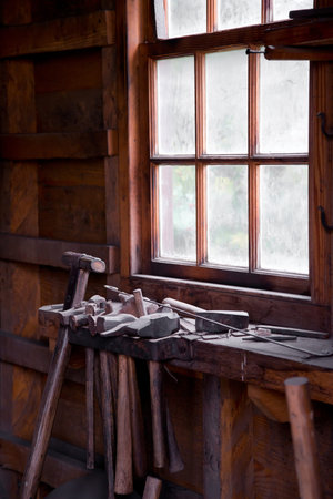 Tools in an old blacksmith forge. A number of hammers of different sizes with wooden handles...