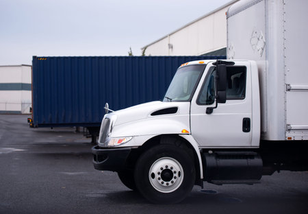 Small economical truck with a box for the local delivery of goods on the parking lot near the store...