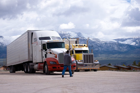 The truck driver goes to his bright yellow attractive custom tuning a big rig semi truck parked in...