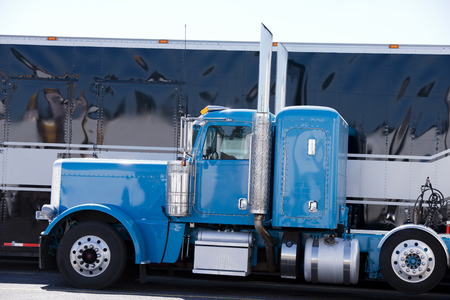 Beautiful classic blue big rig semi truck - a real American style icon among fans and drivers of heavy powerful semi trucks standing on truck stop waiting for the continuation of the movement for a given route for the pick up the cargo trailer and make deの写真素材
