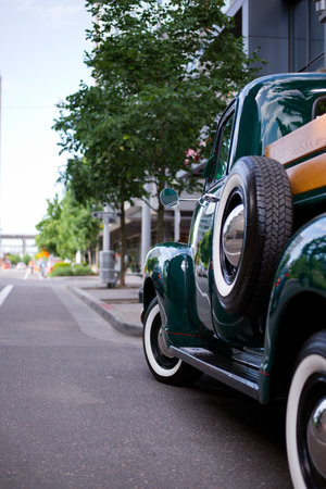Dark Green vintage old truck with a small bodywork, decorated by stained wood piece standing on a long street of a modern city - a great copy for any collector and connoisseur of retro carsのeditorial素材