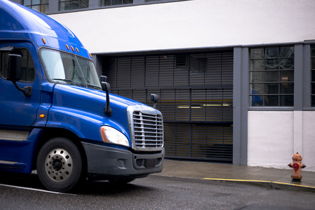 New modern blue large class 8 semi truck with trailer for long haul and local transportation and delivery of cargo and goods from warehouses to retail outlets and businesses on city streetの写真素材