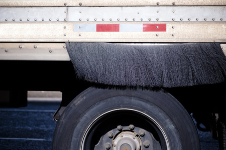 Part of the semi trailer with a wheel and a special brush for cleaning the wheel from dirt and rain dust to ensure safe movement during the delivery of goods to the destination on highway and local roadsの写真素材