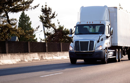 A modern big rig bright white local haul medium-duty semi truck with a day cab with roof spoiler for...