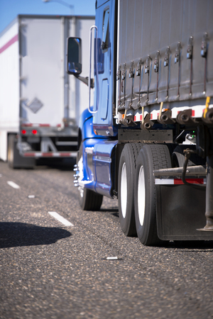 The big rigs semi trucks convoy of different colors, makes and models for long and local haul is moving along the wide multi-lines highwayの写真素材