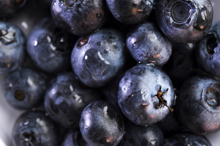 Appetizing healthy delicious and aromatic berries of blueberries shimmer with all shades of dark, reflecting the glare of light in droplets of dewの写真素材