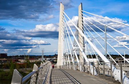 People walking on pedestrian and bicycle path next to the streetcar  and bus roadway through the rope Tilikum Crossing Bridge across the Willamette River in down town Portland Oregonの写真素材