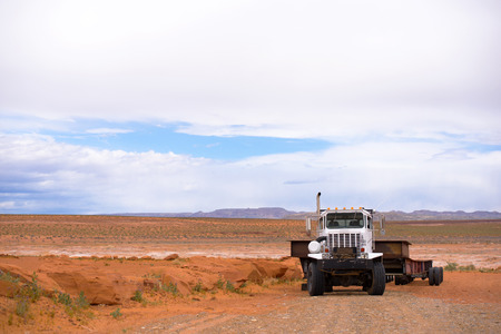 Big rig extra powerful semi tractor with long heavy-duty semi trailer for oversized cargo stand in Arizona desert near the Lake Powell resort awaiting for transportation houseboatsの写真素材